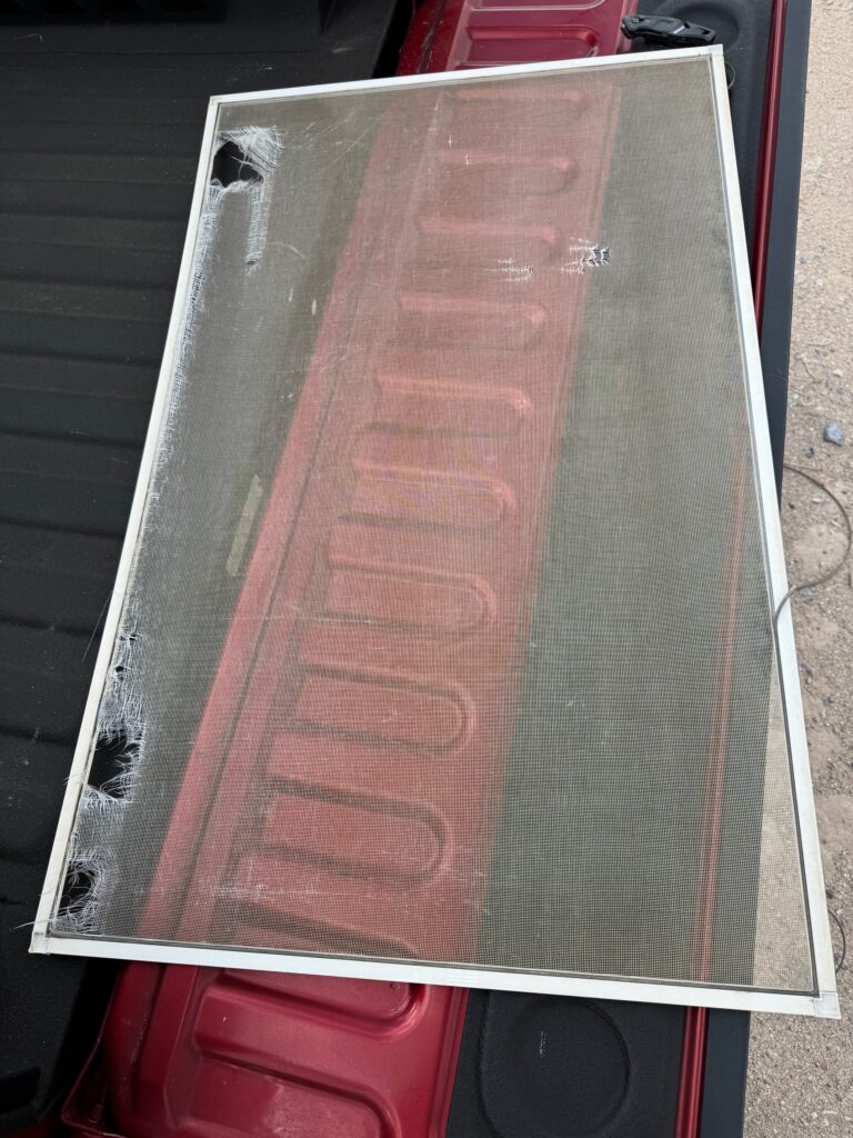 Ripped tattered window screen before being replaced